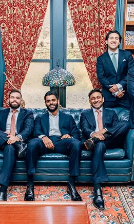 Groomsmen in blue suits posing together in a vintage-style sitting room.