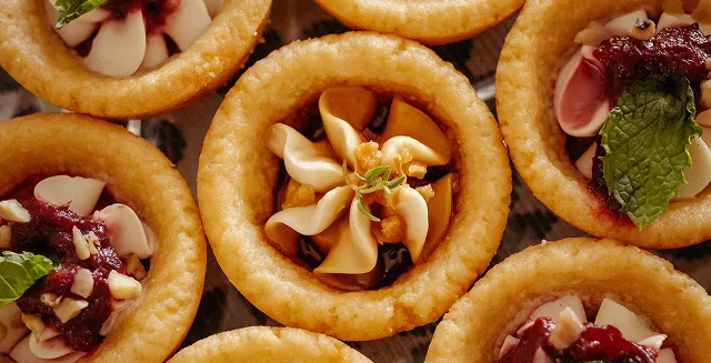 Mini tartlets filled with assorted savory toppings.